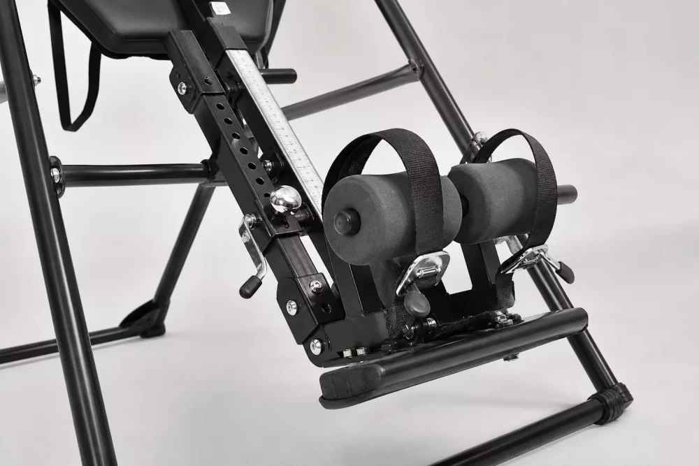 Detailed () image showing a close-up technical view of an inversion table's ankle locking mechanism and adjustment system,