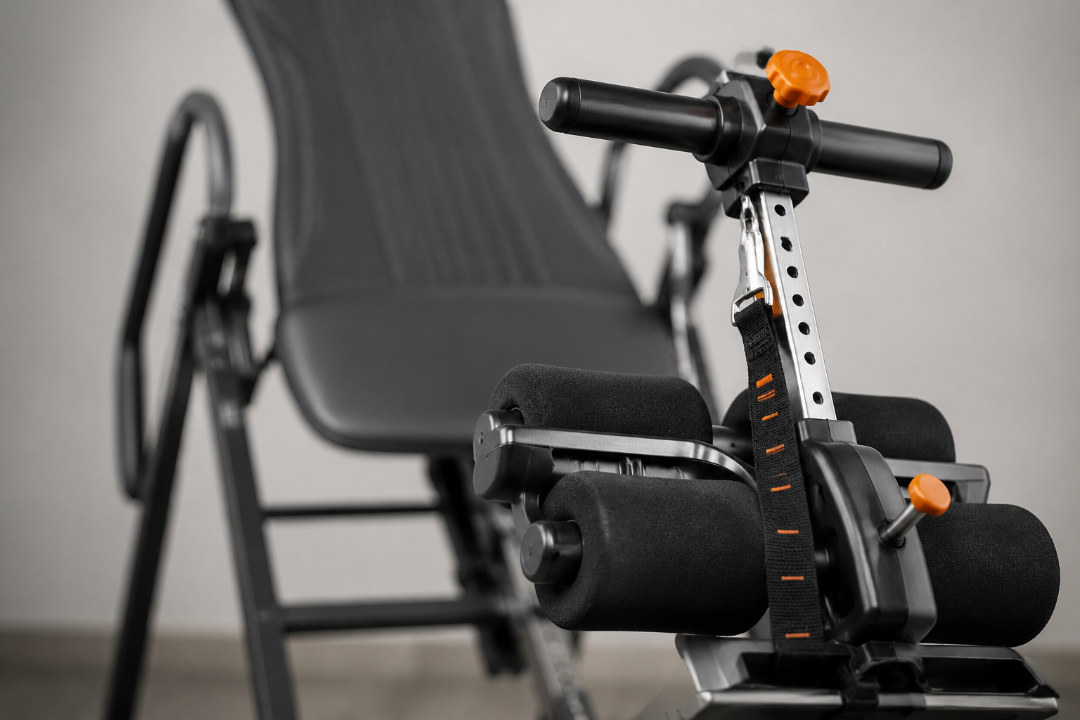 () close-up editorial photograph of an inversion table's ankle support system and angle adjustment mechanism, showing the